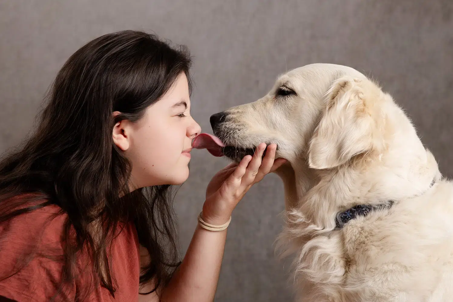 comment photographier son chien Une jeune femme s’approche d’un chien Labrador beige, le museau près du visage et les yeux fermés, dans un moment tendre.